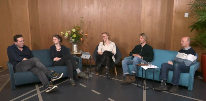 Vijf mensen op stoelen in een halve maan